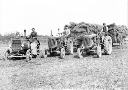 Tre traktorer og vogne læsset med halm